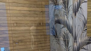 Ein modernes Badezimmer mit einer Holzwandverkleidung, einer Glasdusche und einem Waschtisch.