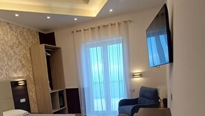 Ein modernes Schlafzimmer mit Bett, Schreibtisch, Stuhl und einem an der Wand befestigten Fernseher.