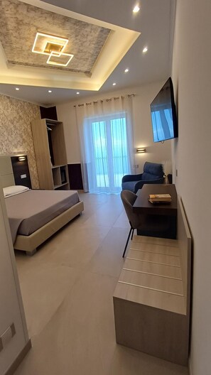 Une chambre à coucher moderne, équipée d’un lit, d’un bureau, d’une chaise et d’un téléviseur fixé au mur.