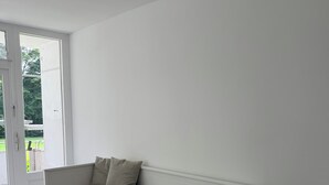 A white, single-bed room with a sliding door to a balcony.