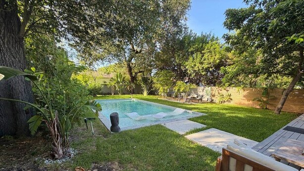 A backyard with a swimming pool, a wooden deck, and a bench. - Home Private Pool • Next from the Design District (Miami)