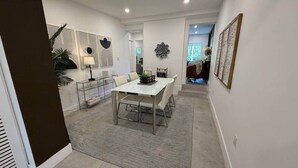 A modern dining area with a white table, grey rug, and contemporary wall art. - Home Private Pool • Next from the Design District (Miami)