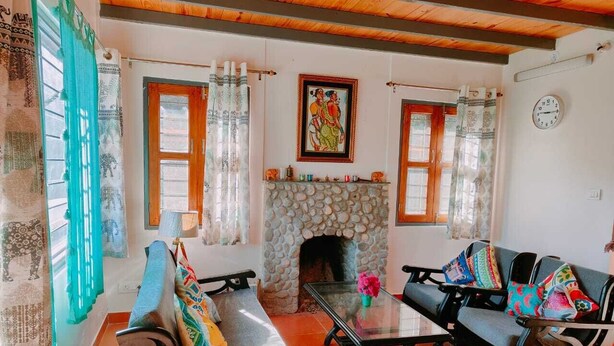 Una sala de estar con chimenea de piedra, dos sofás, una mesa de centro y un reloj de pared.