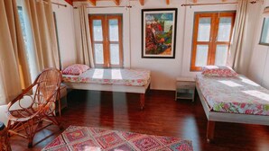 Una habitación con dos camas, techo de madera y un ventanal grande.