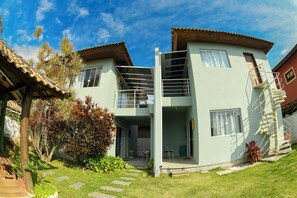 Ein zweistöckiges Haus mit Balkon, einer Treppe und einem kleinen Garten.