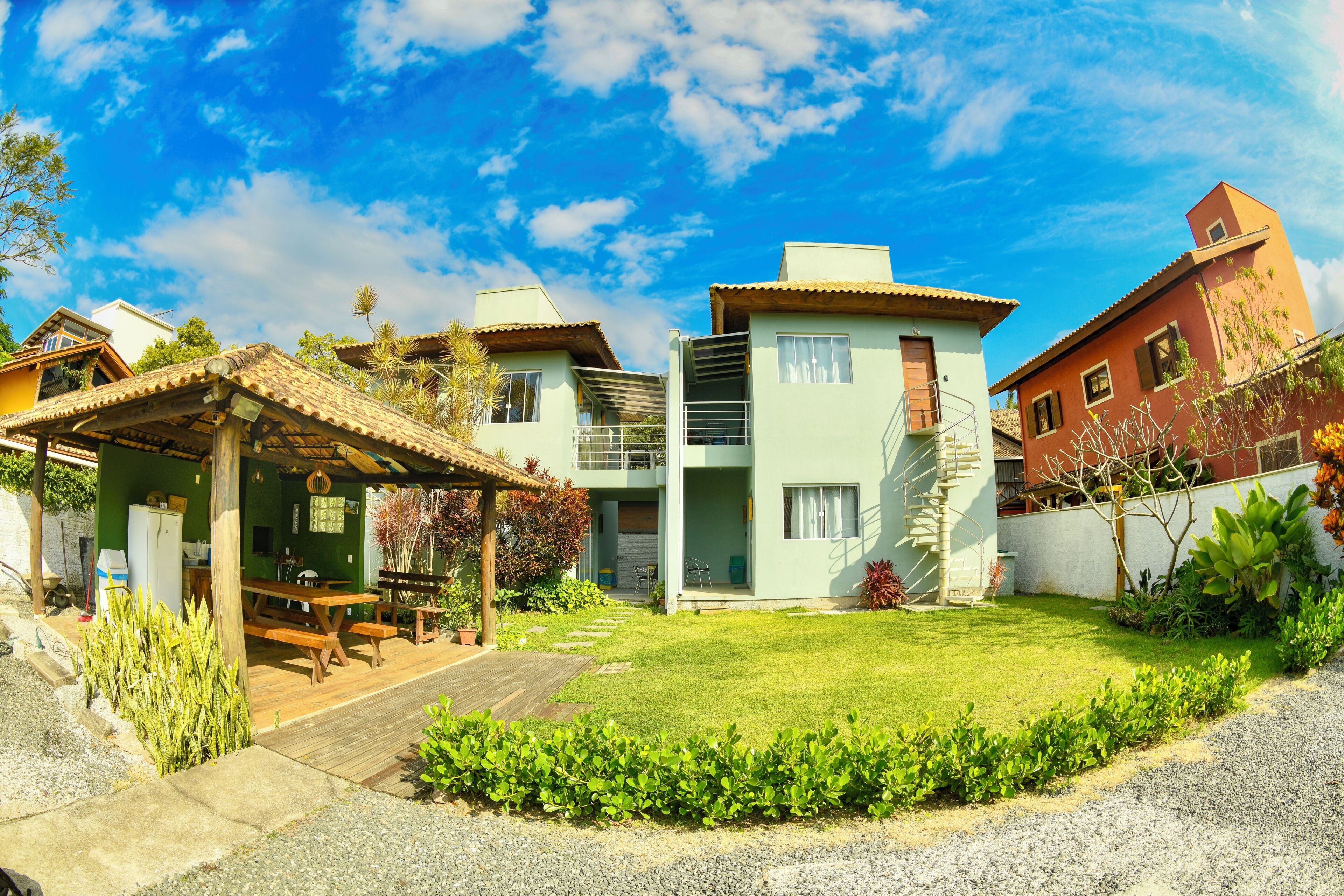 A residential property with a patio, a covered outdoor seating area, a small garden, and a staircase leading to a second-floor balcony.