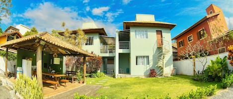 A residential property with a patio, a covered outdoor seating area, a small garden, and a staircase leading to a second-floor balcony.