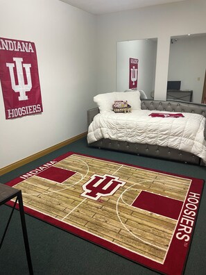 A bedroom with a bed, a basketball court rug, and Indiana Hoosiers decorations.