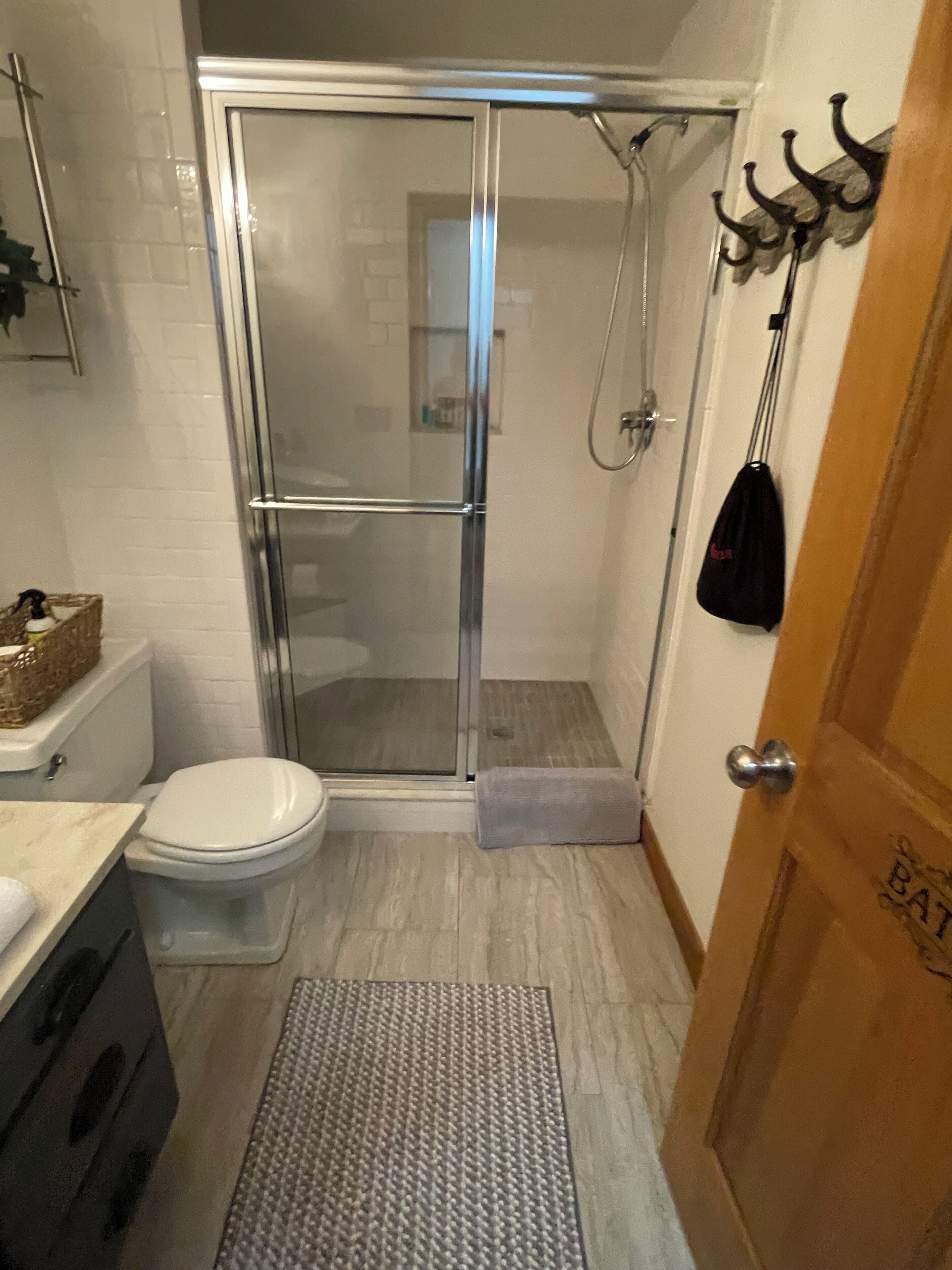 A bathroom with a glass-enclosed shower, a toilet, and a sink.
