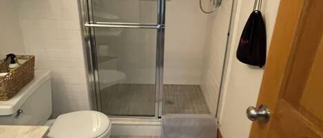 A bathroom with a glass-enclosed shower, a toilet, and a sink.