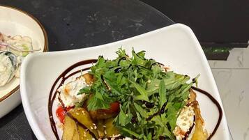 Un saladier blanc contenant une salade, posé sur une surface sombre.