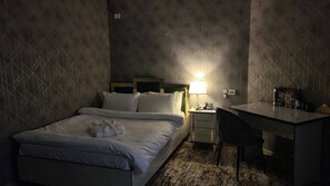 Una habitación de hotel con cama, mesita de noche, escritorio y silla.