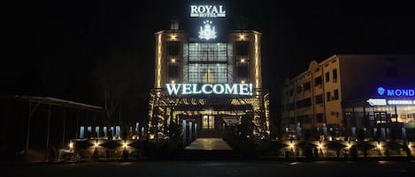 A hotel entrance with a 'WELCOME!' sign, a crown emblem, and a digital display.