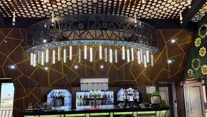 A bar area with a counter, bar stools, and a display of liquor bottles. - Royal Hotel Navoi (Navoiy)