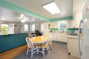 Una cocina con mesa, sillas, refrigerador y un sofá color turquesa.
