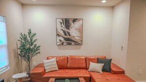 Una sala de estar con un sofá de cuero, una mesa de centro, un cuadro en la pared y una planta en maceta.