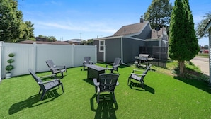 A backyard with artificial grass, a barbecue grill, and outdoor furniture.