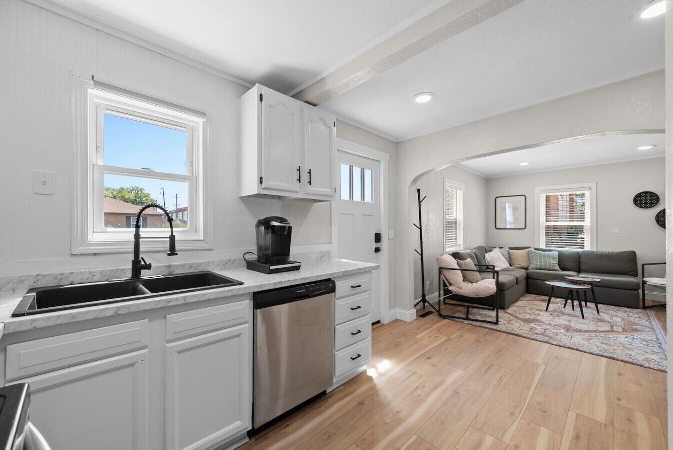 A modern kitchen with white cabinetry, a coffee maker, and a dishwasher.