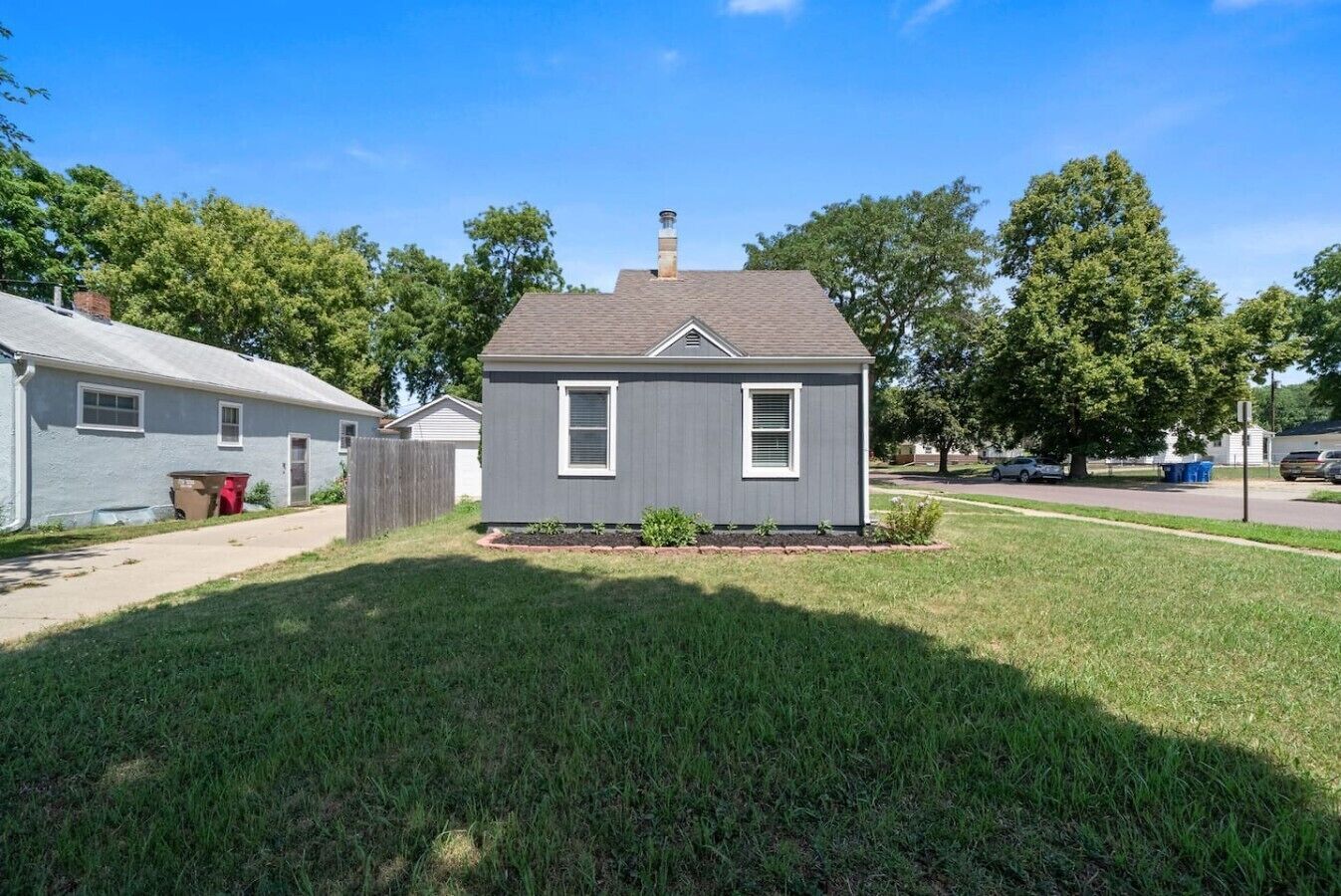 A single-story house with a front yard, a chimney, and a small garden area.