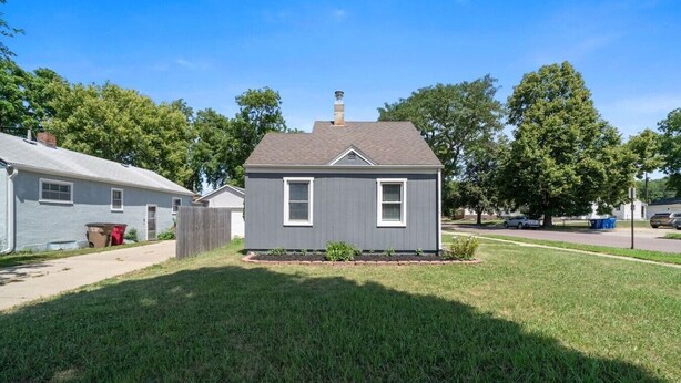 A single-story house with a front yard, a chimney, and a small garden area.