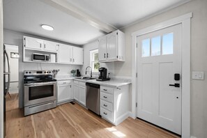 Una cocina moderna con armarios blancos, electrodomésticos de acero inoxidable y lavavajillas.