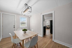 Un comedor moderno con una mesa de madera, sillas blancas y una lámpara.