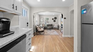 A modern kitchen with a coffee maker, a dining area with a sofa and chairs, and a refrigerator.