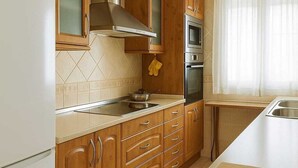 A kitchen with wooden cabinets, a stainless steel range hood, a built-in oven, and a large island with a sink. - Rural House 8 km from Cuenca (World Heritage Site) (Villar de Olalla)