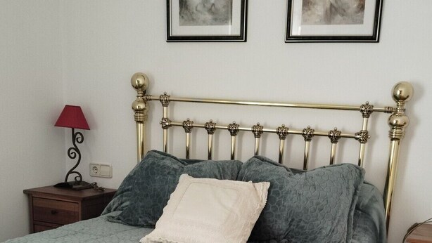 A bed with a patterned bedspread, a decorative headboard, and a nightstand with a lamp. - Rural House 8 km from Cuenca (World Heritage Site) (Villar de Olalla)