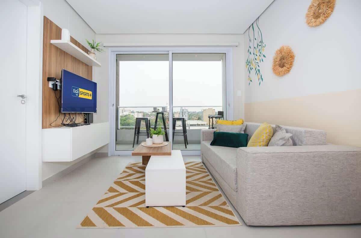 Una sala de estar moderna con un sofá, una mesa de centro y un televisor montado en la pared.