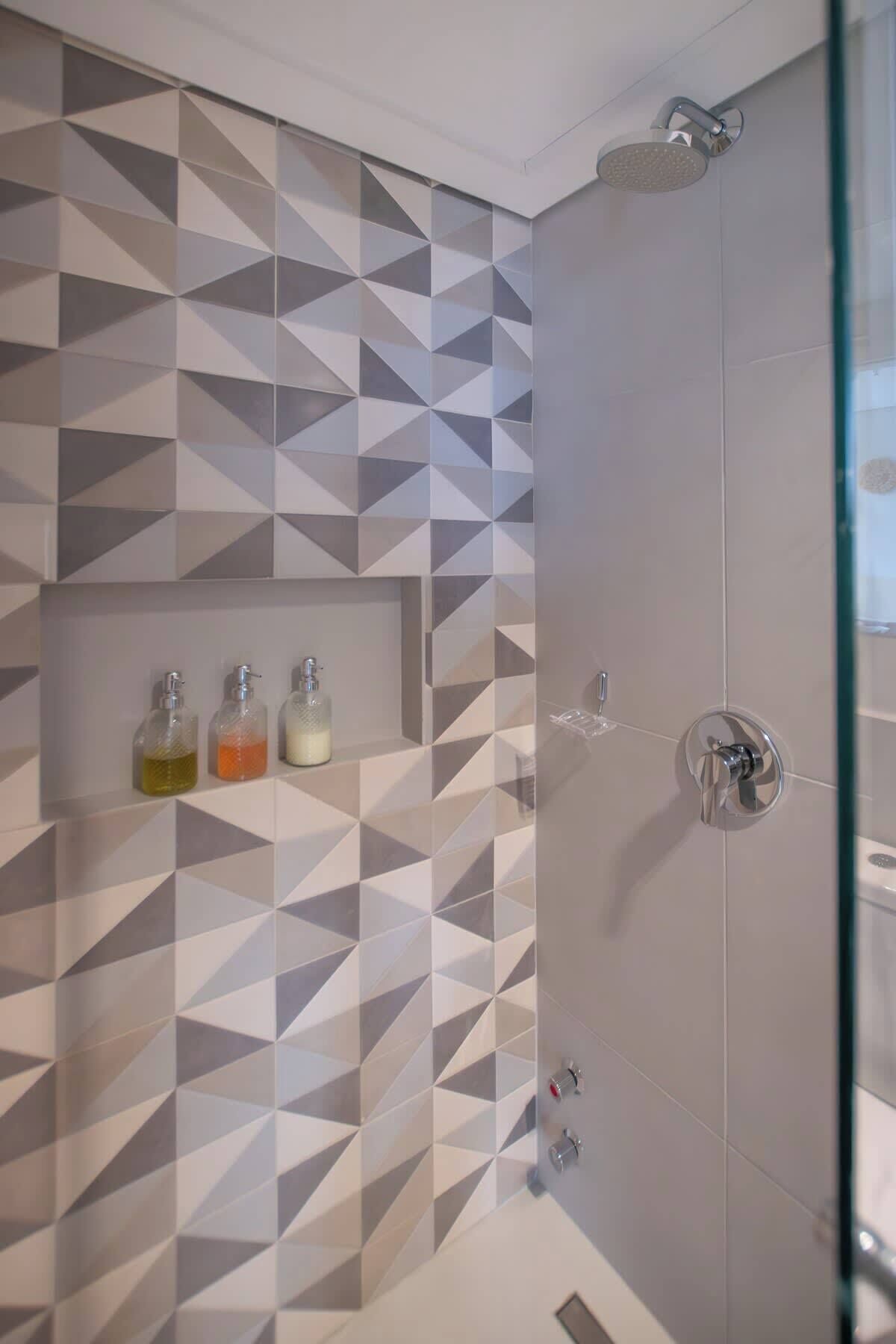 A shower with a geometric tile pattern, a glass enclosure, and a showerhead.