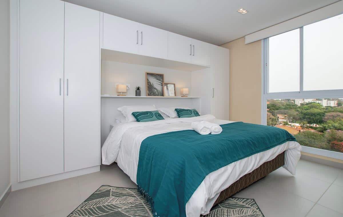 Un dormitorio moderno con una cama grande, un armario blanco y vistas a la ciudad.
