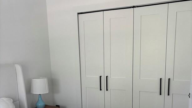 Une chambre à coucher avec un lit, une table de chevet avec une lampe et une armoire.