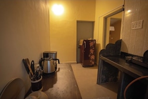 A narrow hallway with a coffee maker, a kettle, and a refrigerator. - Heritage Haven (Ashwem)