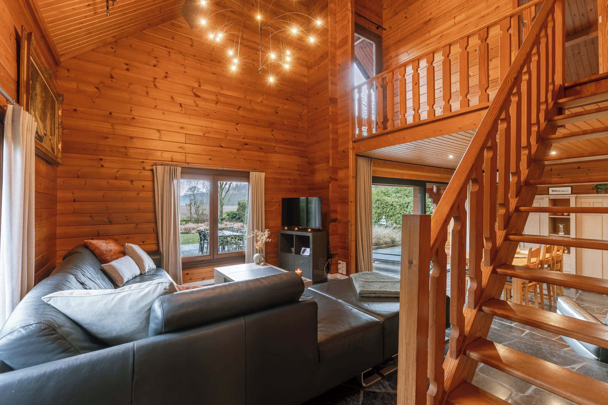 A wooden cabin interior with a sofa, TV, and a staircase.