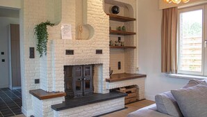 Un salon avec une cheminée, un canapé et une fenêtre avec des rideaux.