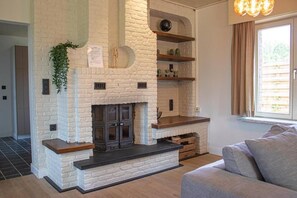 A living room with a fireplace, a sofa, and a window with curtains. - Lammersdamhoeve - between Ghent & Bruges (Wingene)