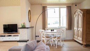 Un salon comprenant un canapé, un téléviseur, une table à manger, des chaises et un meuble.