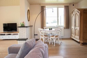 A living room with a sofa, TV, dining table, chairs, and a cabinet. - Lammersdamhoeve - between Ghent & Bruges (Wingene)