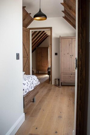 A bedroom with a wooden floor, a bed with a patterned bedspread, a hanging light fixture, and a wardrobe. - Lammersdamhoeve - between Ghent & Bruges (Wingene)