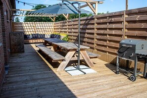 An outdoor patio with wooden benches, a grill, and a pergola with string lights. - Lammersdamhoeve - between Ghent & Bruges (Wingene)