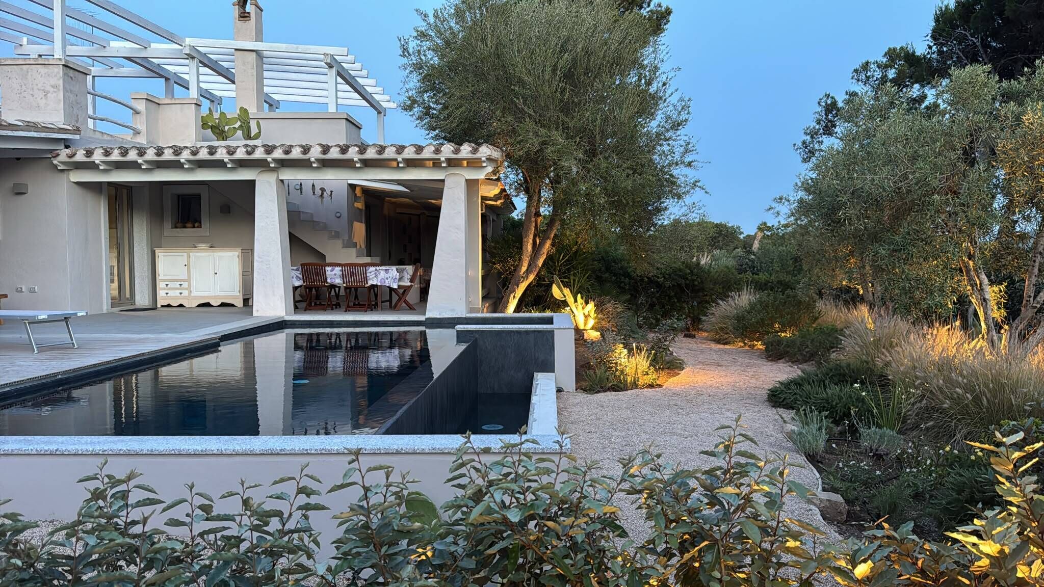 A modern house with a swimming pool, outdoor seating, and a garden path.