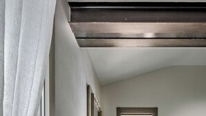 Une chambre à coucher avec un lit, une salle de bain visible à travers une porte, et un tableau accroché au mur.