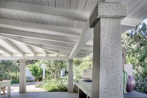 A covered outdoor area with a wooden ceiling and concrete pillars. - House Among the Olive Trees (villasimius)