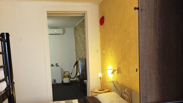 Habitación de hotel con una litera, una mesita de noche con lámpara y un armario de madera.