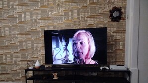 Un televisor sobre un mueble con un fondo de papel tapiz estampado.