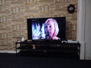 Ein Fernseher auf einem Ständer vor einer Tapete mit Muster.