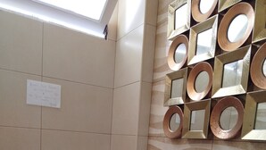 Un baño con un inodoro blanco, un lavabo con lavamanos curvo y un espejo montado en la pared con marcos circulares.