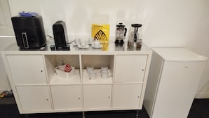 Una kitchenette con cafetera, licuadora y molinillo de café sobre la encimera.