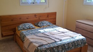 A bedroom with a wooden bed, a bedside table, a dresser, and a window with curtains. - Joss location  971 (Le Gosier)